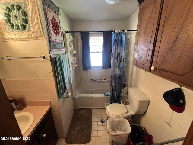 full bathroom with a wainscoted wall, toilet, vanity, tile walls, and shower / bathtub combination with curtain