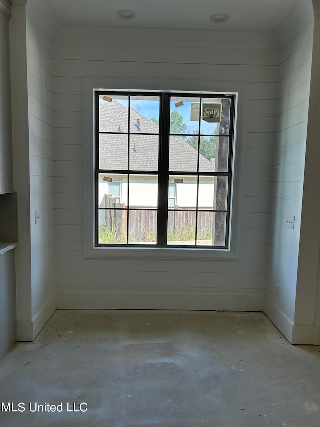 unfurnished room with a healthy amount of sunlight and wooden walls