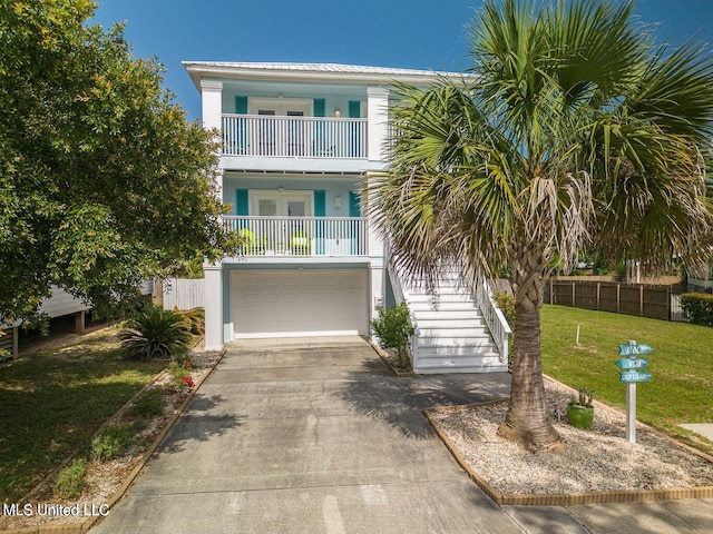 coastal home with a balcony, stairs, a front yard, and stucco siding