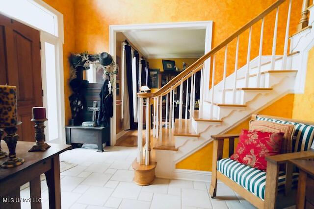 entrance foyer with baseboards, stairs, and stone tile floors