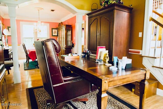 office area with crown molding, arched walkways, ornate columns, and wood finished floors