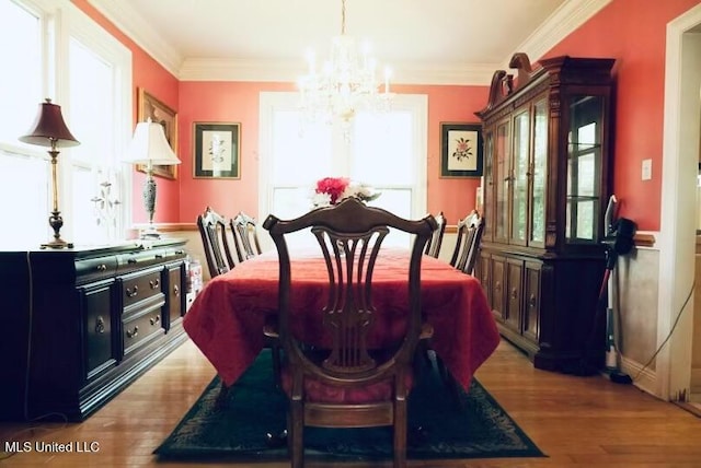 dining room with an inviting chandelier, crown molding, and wood finished floors