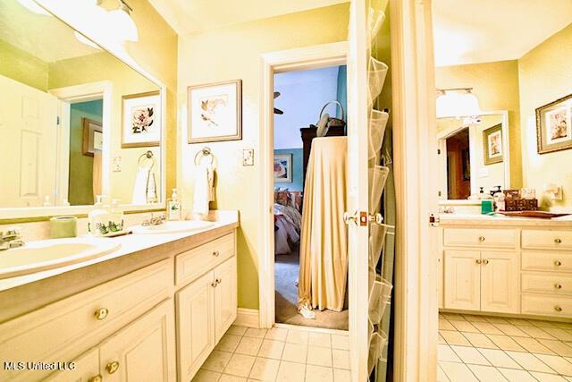 ensuite bathroom featuring double vanity, tile patterned floors, ensuite bath, and a sink