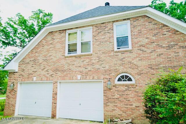 view of side of property with an attached garage, concrete driveway, and brick siding