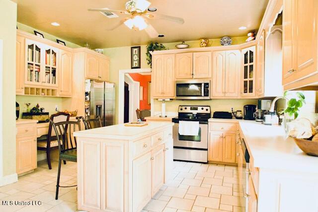 kitchen with a ceiling fan, appliances with stainless steel finishes, a center island, light countertops, and recessed lighting