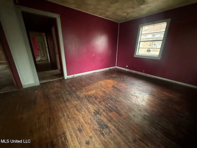 spare room with wood-type flooring and baseboards