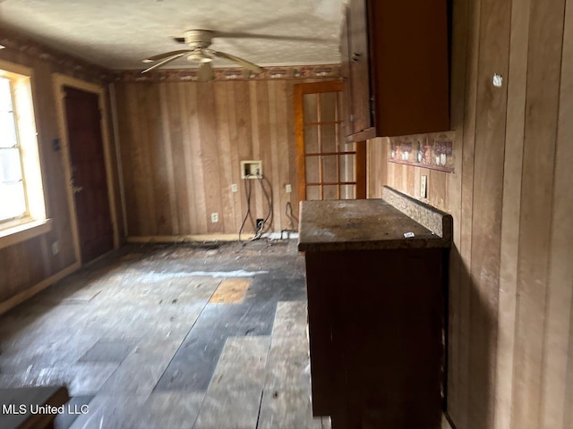 interior space featuring dark countertops, wood walls, and ceiling fan