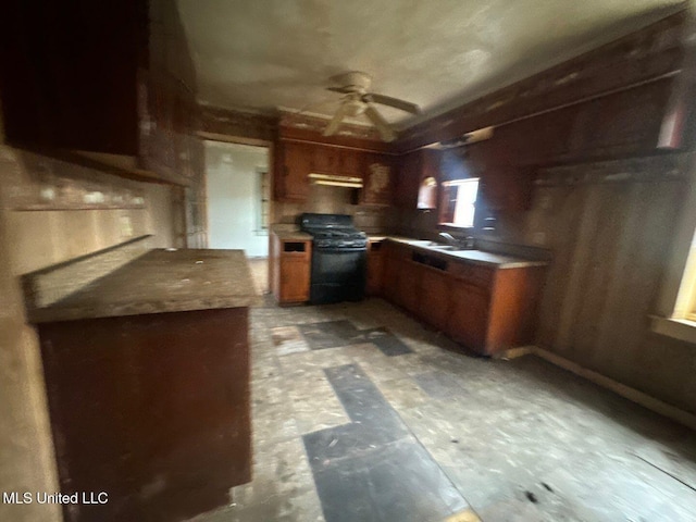 kitchen with brown cabinetry, ceiling fan, black gas stove, a sink, and exhaust hood