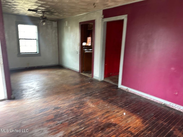 spare room featuring a ceiling fan, hardwood / wood-style flooring, and baseboards