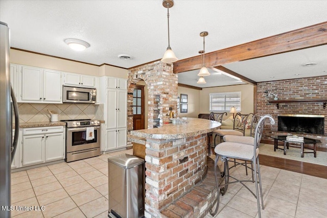 kitchen with light tile patterned floors, stainless steel appliances, hanging light fixtures, and white cabinets