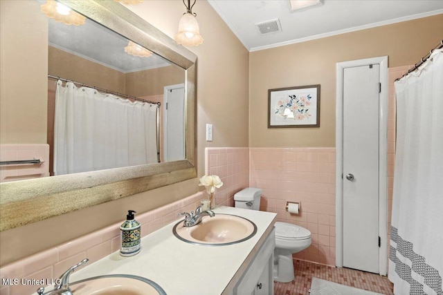 bathroom with ornamental molding, visible vents, a sink, and tile walls