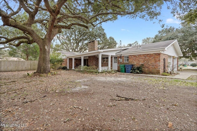 view of front of house with a garage, brick siding, fence, and a chimney