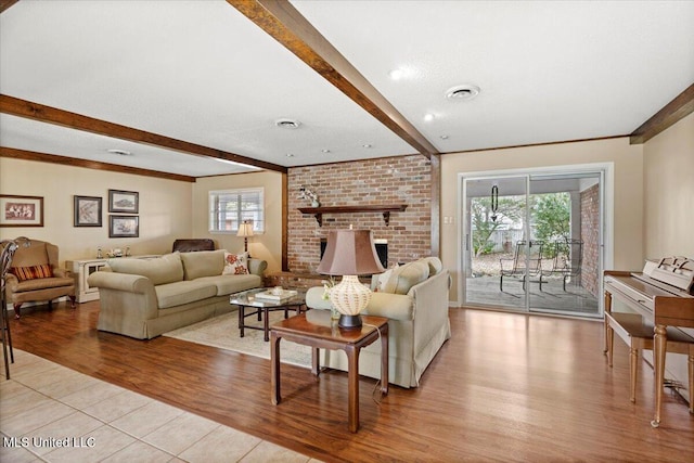 living area featuring light wood-style floors, beam ceiling, visible vents, and a fireplace