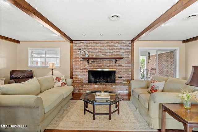 living room featuring a brick fireplace, beamed ceiling, and a textured ceiling