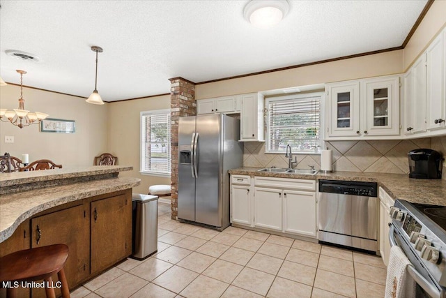 kitchen featuring decorative light fixtures, a sink, white cabinets, appliances with stainless steel finishes, and glass insert cabinets