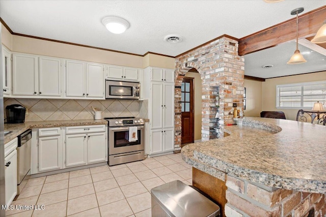 kitchen featuring stainless steel appliances, hanging light fixtures, light countertops, and white cabinetry