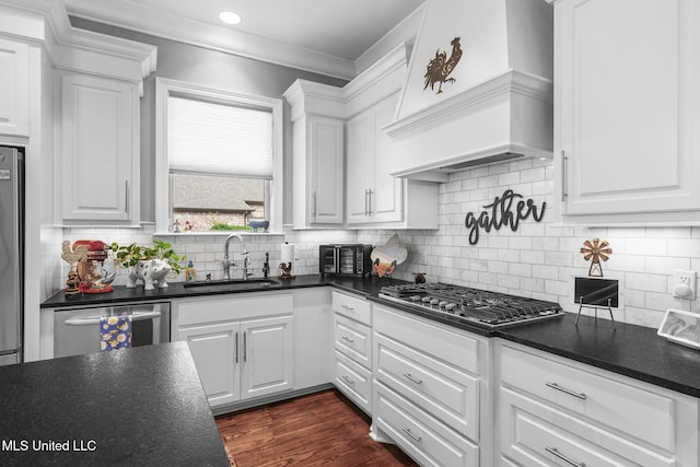 120 Saddlebrook Cv, Madison, MS 39110 - kitchen with appliances with stainless steel finishes, dark countertops, premium range hood, white cabinetry, and ornamental molding