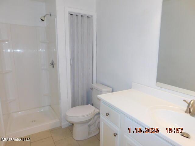 bathroom with walk in shower, tile patterned flooring, vanity, and toilet