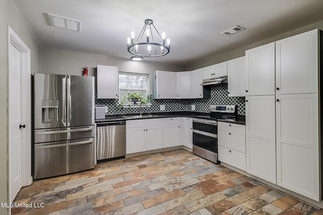 kitchen featuring sink, appliances with stainless steel finishes, white cabinetry, hanging light fixtures, and decorative backsplash