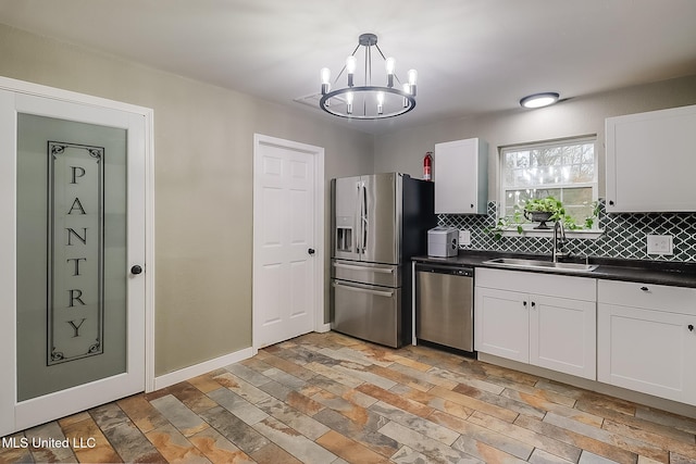 kitchen featuring pendant lighting, sink, white cabinetry, backsplash, and stainless steel appliances