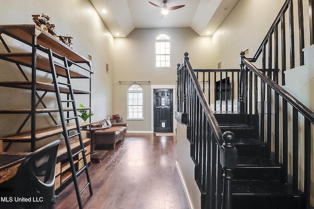 stairs featuring hardwood / wood-style flooring, ceiling fan, and high vaulted ceiling