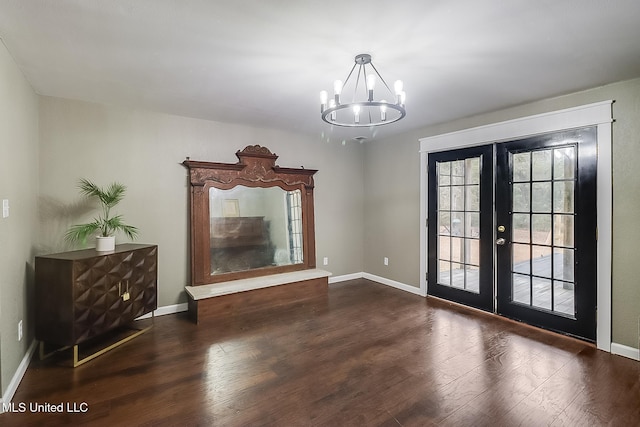 unfurnished dining area featuring french doors, dark hardwood / wood-style flooring, and an inviting chandelier