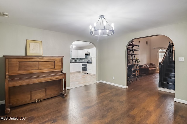 miscellaneous room with dark wood-type flooring and an inviting chandelier