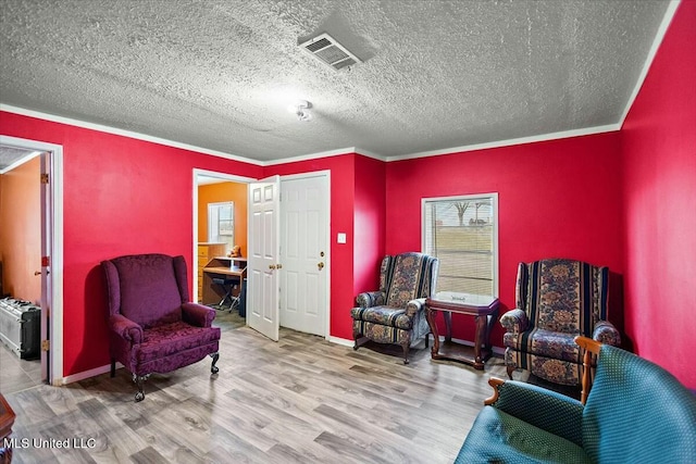 sitting room featuring crown molding, wood-type flooring, and a textured ceiling