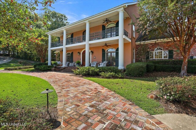 607 Tiffintown Rd, Vicksburg, MS 39183 - greek revival inspired property with a front lawn, a porch, a balcony, ceiling fan, and stucco siding