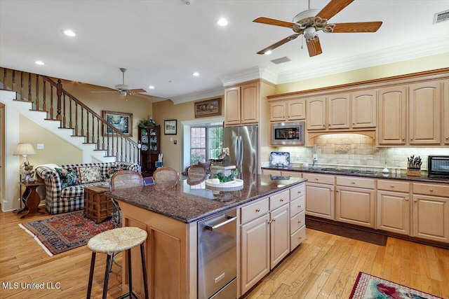 607 Tiffintown Rd, Vicksburg, MS 39183 - kitchen featuring light wood finished floors, a breakfast bar, a ceiling fan, tasteful backsplash, and appliances with stainless steel finishes