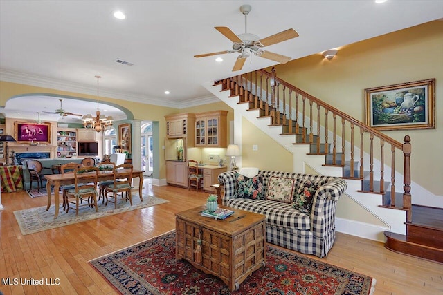 607 Tiffintown Rd, Vicksburg, MS 39183 - living room with stairway, arched walkways, light wood-type flooring, crown molding, and ceiling fan with notable chandelier