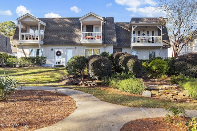 view of front of home with a balcony and a front lawn