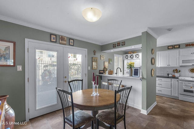 dining space with french doors and crown molding