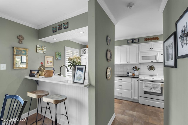 kitchen featuring white cabinets, range with electric stovetop, a kitchen bar, and crown molding