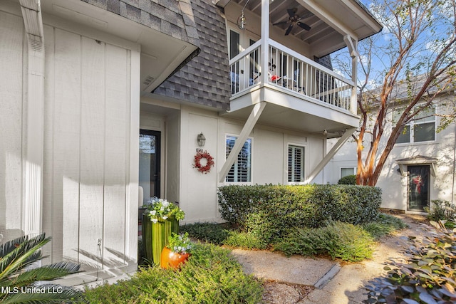 view of exterior entry with a balcony and ceiling fan