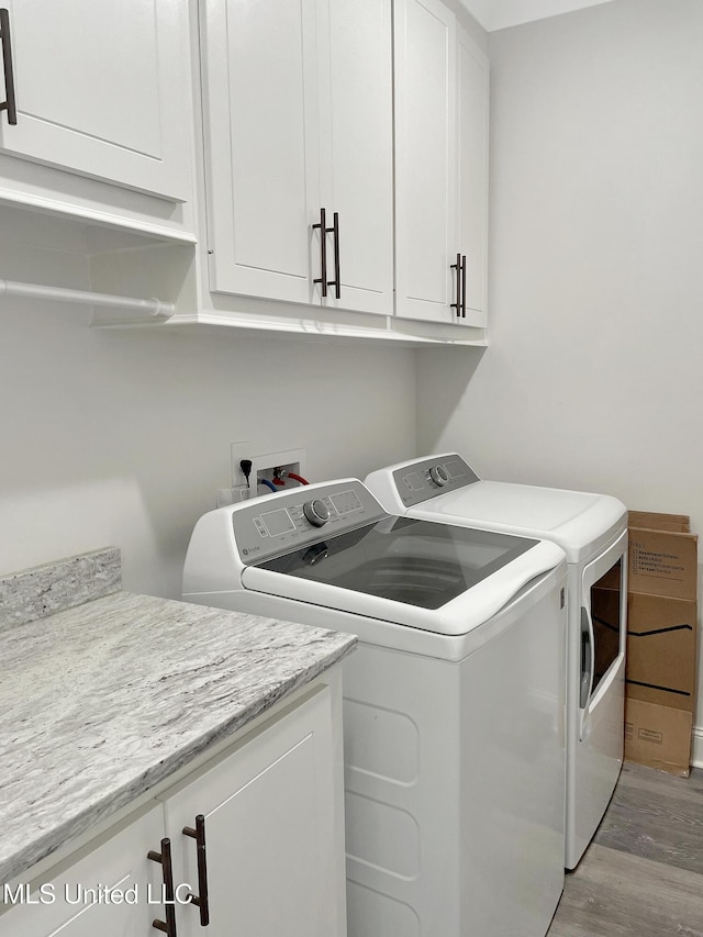 washroom with cabinets, light hardwood / wood-style floors, and washer and dryer