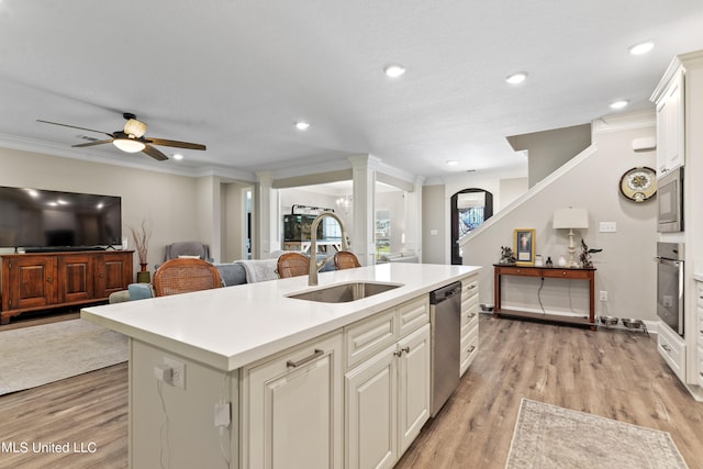 kitchen featuring an island with sink, light hardwood / wood-style flooring, sink, crown molding, and appliances with stainless steel finishes