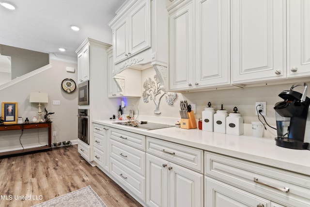 kitchen with ornamental molding, appliances with stainless steel finishes, light hardwood / wood-style flooring, and white cabinetry