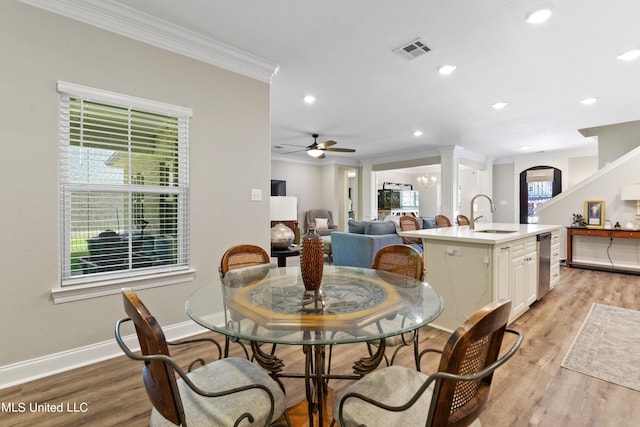 dining space with light hardwood / wood-style floors, ornamental molding, sink, and ceiling fan