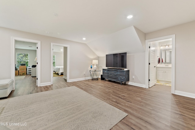 bedroom featuring vaulted ceiling, ensuite bathroom, and light wood-type flooring