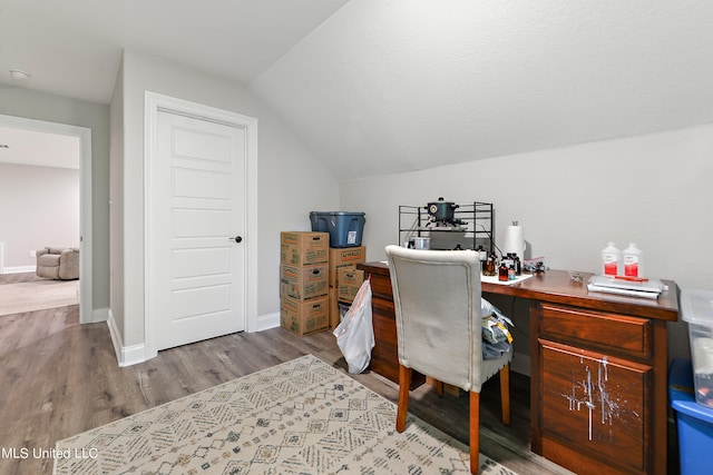 home office featuring vaulted ceiling and light hardwood / wood-style flooring