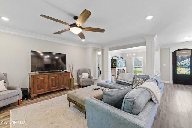 living room featuring crown molding, ornate columns, ceiling fan with notable chandelier, and light hardwood / wood-style floors