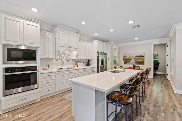 kitchen with white cabinetry, a breakfast bar, appliances with stainless steel finishes, and sink