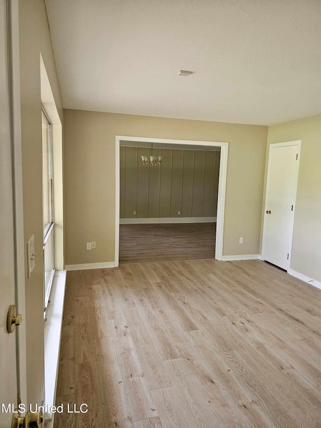 unfurnished bedroom featuring a notable chandelier and light wood-type flooring