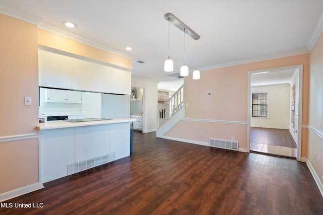 kitchen featuring white cabinetry, hanging light fixtures, dark wood-type flooring, kitchen peninsula, and ornamental molding