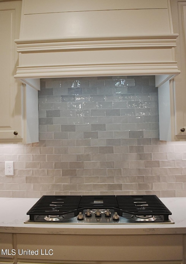 details with light stone countertops, cream cabinets, tasteful backsplash, and stainless steel gas stovetop