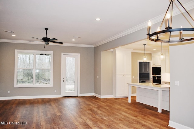 interior space featuring hardwood / wood-style floors, ceiling fan with notable chandelier, ornamental molding, and sink