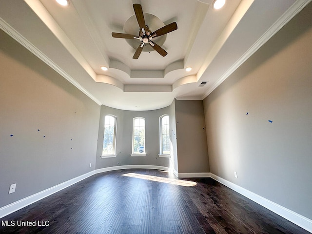 spare room featuring a tray ceiling, ceiling fan, crown molding, and dark hardwood / wood-style floors