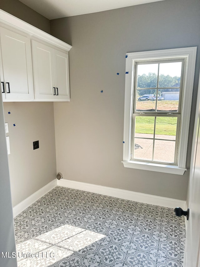 laundry area with hookup for an electric dryer, cabinets, and light tile patterned floors