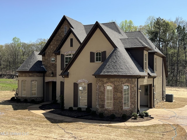 145 Poplar Ln, Holly Springs, MS 38635 - french country inspired facade with stone siding, central AC unit, roof with shingles, and brick siding